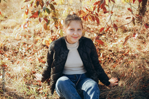 teenage girl in the autumn garden. the girl near the trees with yellow leaves is autumn time. portrait of a girl with yellowed leaves