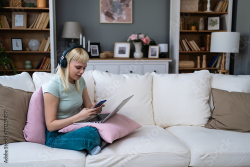 Taking a break. Young freelance business woman respond on text messages on her smartphone in pause of work on laptop computer. Online working at home, female online dating during the day.