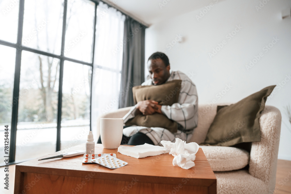 Sitting on sofa, holding pillow. Sick black man is at home Sitting on sofa, holding pillow. Sick black man is at home
