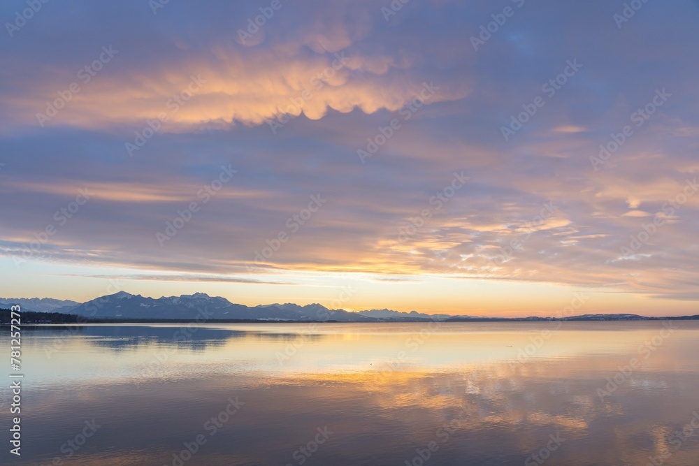Sunset on the lake with mountains in the background and clouds in the sky