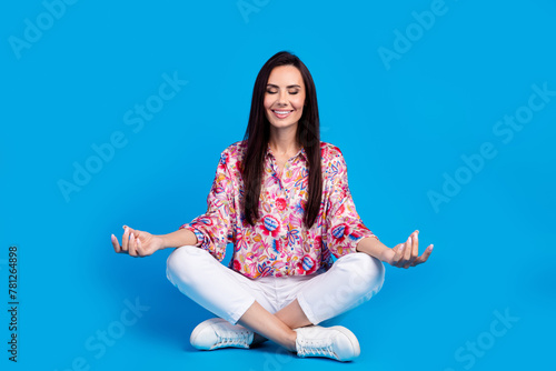 Full length photo of dreamy adorable lady dressed print shirt sitting legs crossed practicing yoga isolated blue color background photo