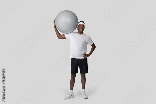 Casual man holding exercise ball at side smiling © Prostock-studio