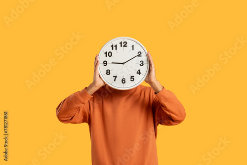 Man holding clock in front of face photo