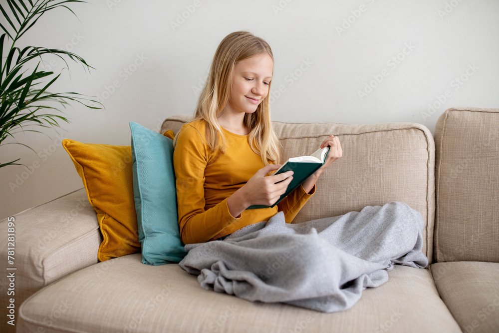 Teen Girl Enjoying a Book on a Cozy Sofa in Daylight Teen Girl Enjoying a Book on a Cozy Sofa in Daylight