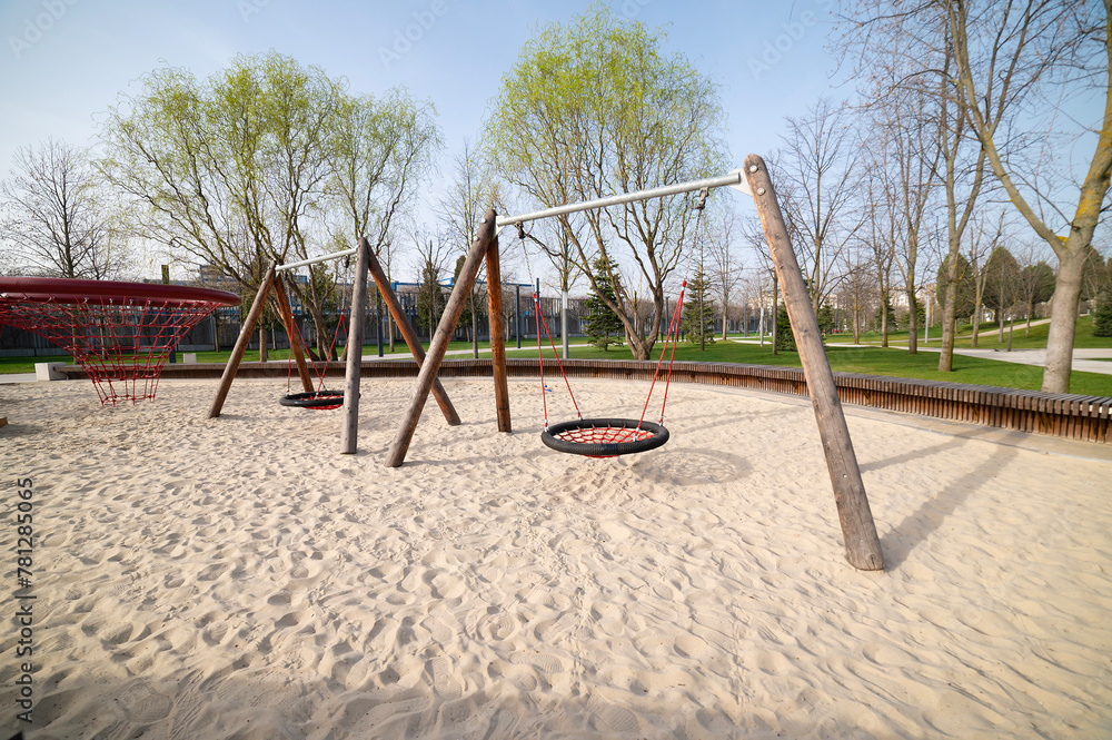 Fototapeta premium Swings on a sand-covered playground. Entertainment complex for children's games.