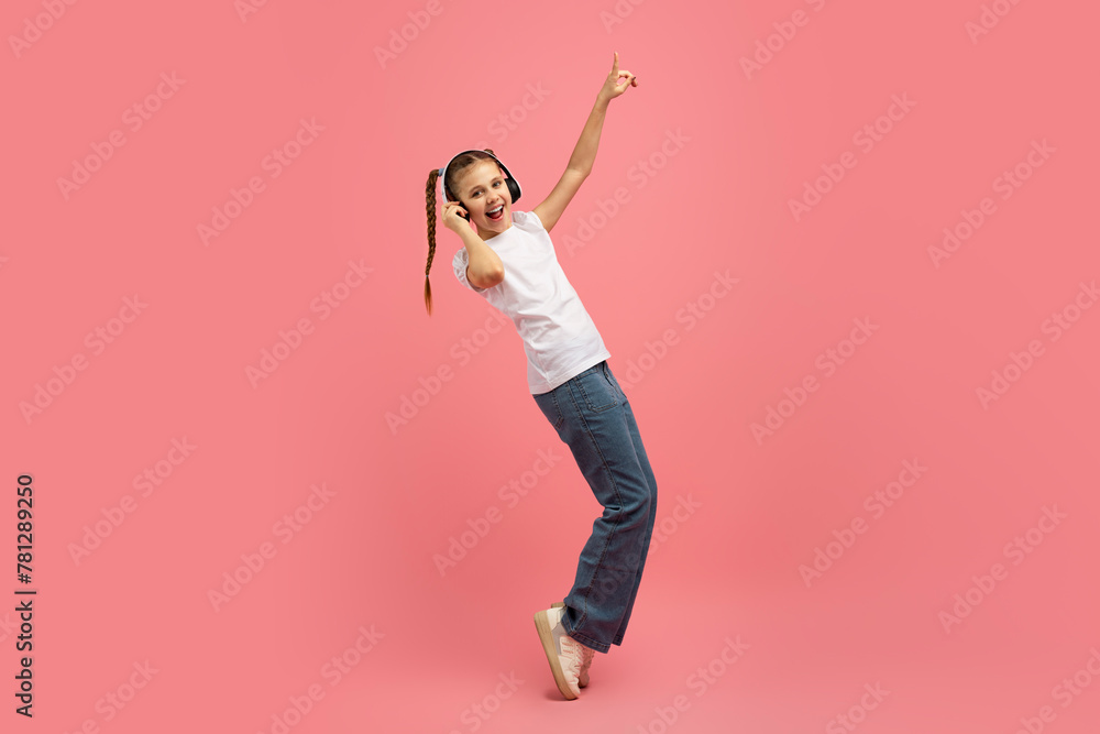 Excited girl jumping with joy on pink backdrop