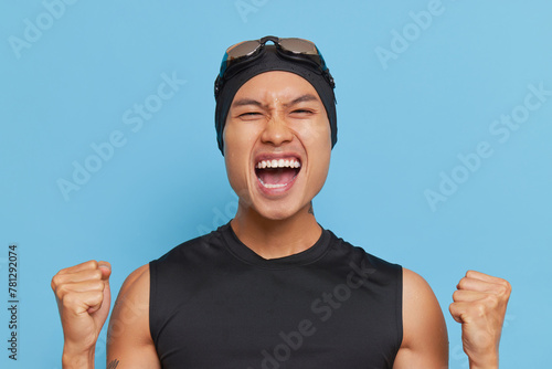 Hand gesture signal as he raises fists in air, wearing swimming cap and goggles photo
