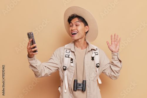 Man in costume hat and long sleeve shirt smiling, snapping selfie with phone