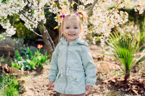 Smiling beauty girl in jacket in spring blooming garden. © artifirsov