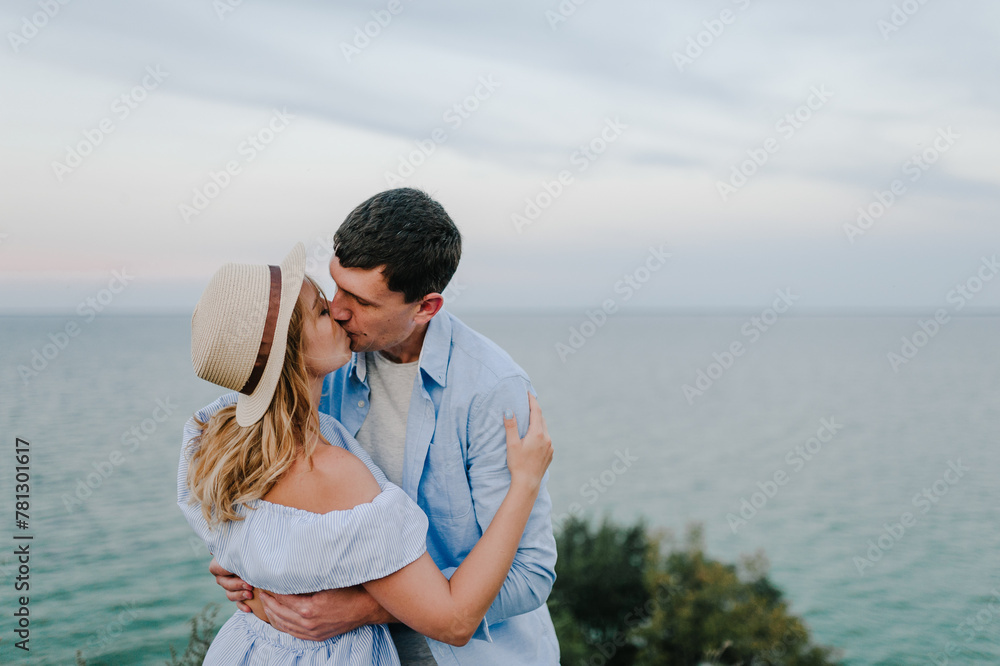 Man and woman kiss and embrace on sand sea spending time together couple. Couple in love standing and kissing on edge of cliff on seashore. Female and male on beach ocean and enjoying sunny summer day