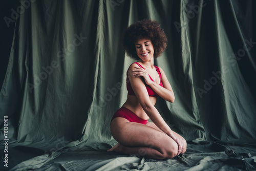 Unretouched photo of happy woman sit knees touch gentle body hand isolated khaki linen background © deagreez