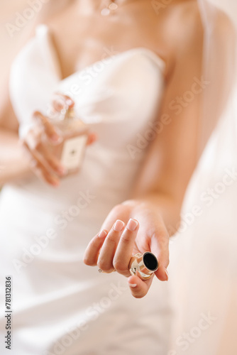 Gorgeous bride in stylish wedding dress sprays perfume on herself. Woman stand in bathroom