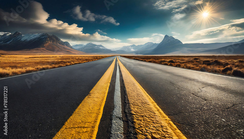 An empty road leading towards distant mountains with distinct yellow lane markings, emphasizing the asphalt texture.