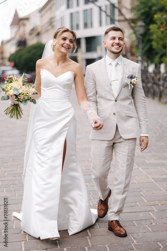 Newlyweds walking in the city centre in Europe. Beautiful wedding couple surrounded of old architecture 