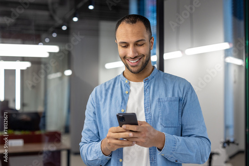 Smiling businessman using smartphone in modern office