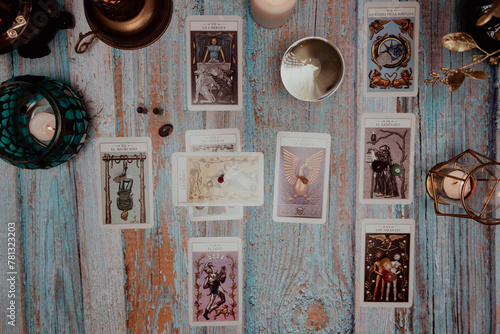 A dimly lit scene showing a spread of tarot cards, alongside crystals, candles, and a crystal ball on a rustic wooden table.