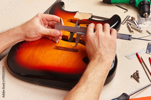 Guitar master measures size of holes for tremolo in body of guitar with caliper.