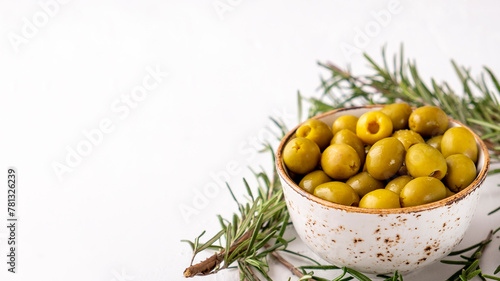 Marinated green olives in a bowl on white background. Copy space
