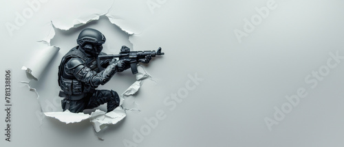 A motionless soldier hidden partially by paper aims their rifle through a strategically torn hole in white paper photo