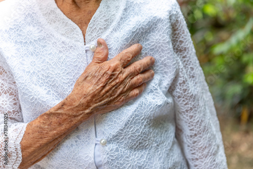 Senior woman suffering from chest pain while walking in the garden.