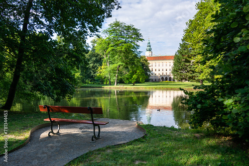 A romantic spot with wooden bench by the pond in the Chateau Garden with a view of the Archbishop's Castle in Kroměříž, a UNESCO World Heritage Site