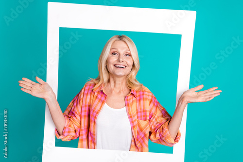 Portrait of charming lovely retired woman wear plaid trendy clothes hands hold photo card image isolated on cyan color background photo