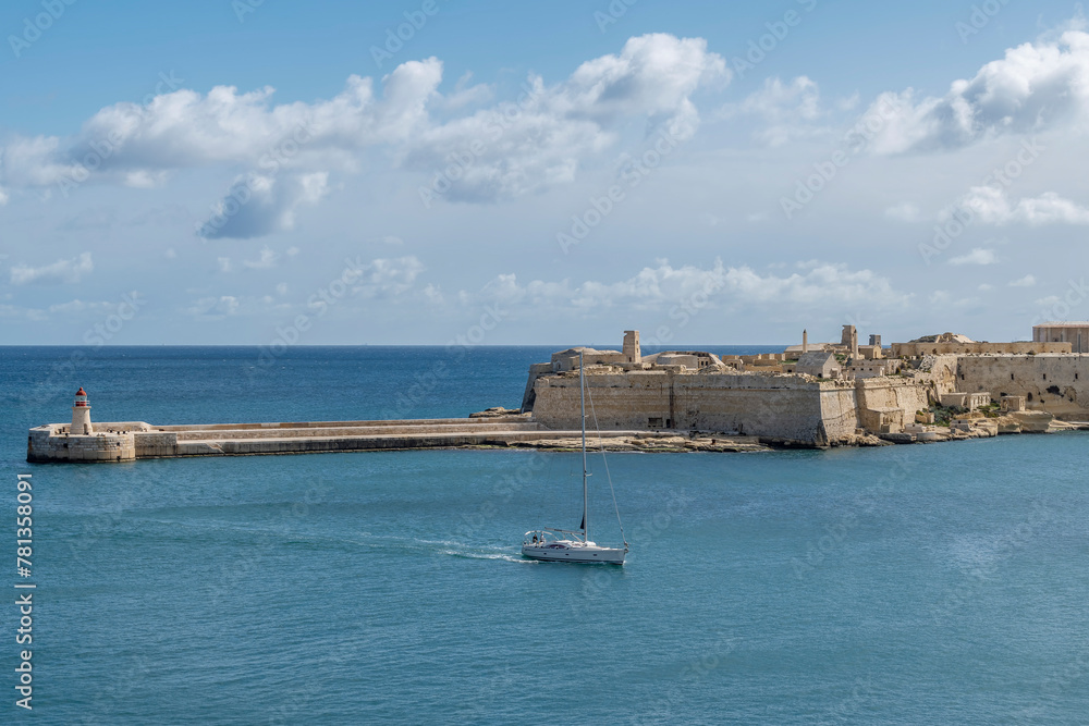 A boat enters Valletta Bay passing near the Ricasoli East Breakwater, Kalkara, Malta
