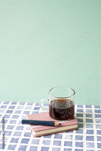 Diary notebook, pencil, coffee on blue tile desk. mint wall background. workspace