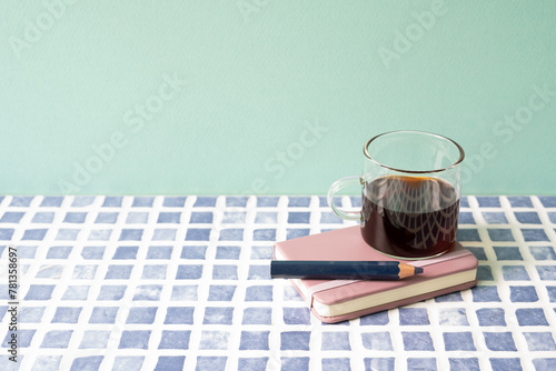 Diary notebook, pencil, coffee on blue tile desk. mint wall background. workspace