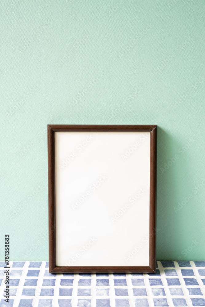 Wooden picture frame on blue tile shelf. mint wall background. copy space