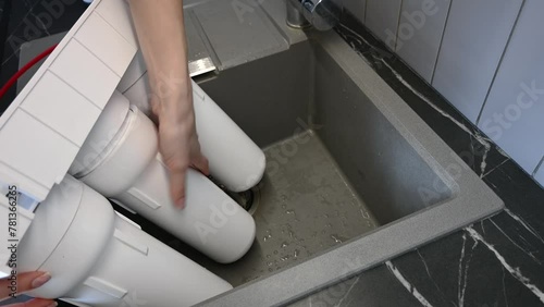 Woman installing water filter cartridges in a kitchen. Installation of water purification system