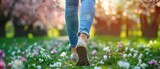 Portrait of a woman leg walking through a flower garden wearing denim pants and sneakers with a big space a spring flower garden, Generative AI.