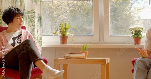 Fototapeta Two women conversing while seated in armchairs