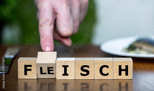 Hand turns cube and changes the German word 'Fleisch' (meat) to 'Fisch' (fish). Symbol for eating more healthy and choosing fish instead of meat.