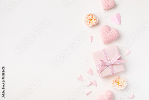 Greeting card for Birthday, Woman or Mothers Day. Pink hearts, rose flowers and gift box on table top view. Flat lay.
