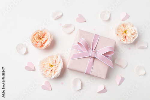 Birthday, Woman or Mothers Day greeting card. Pink hearts, rose flowers and gift box on pastel table top view. Flat lay.