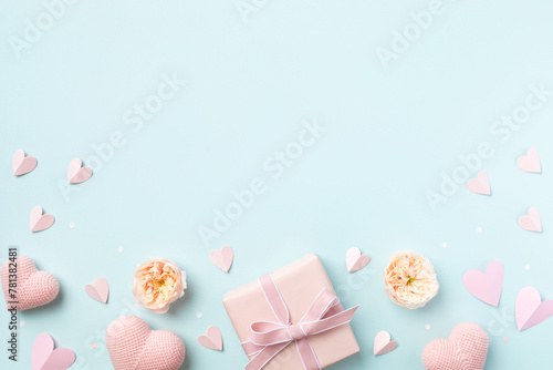 Pink gift or present, rose flowers and decorative hearts on blue background top view. Birthday, Woman or Mothers Day greeting card. © juliasudnitskaya