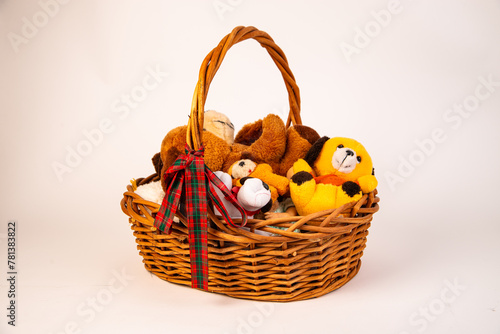 Woven basket with handle full of stuffed animals on a white background.
