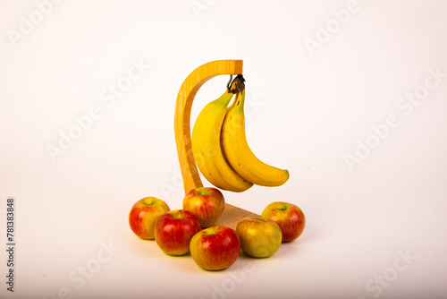 Bananas on a stand with honeycrisp apples around the base on a white background.