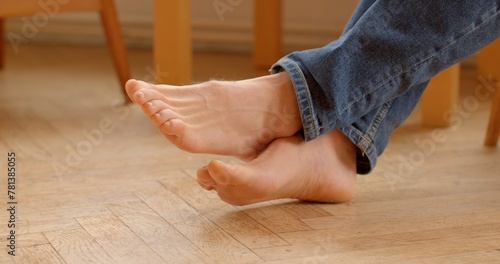 Fotografie Bare male feet rest comfortably on the smooth parquet floor, legs in jeans, exuding a sense of relaxation and intimacy