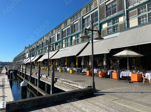 Apartments in rows near a marina dock. Buildings and a quay in a harbour district. Street and boardwalk in a port city.