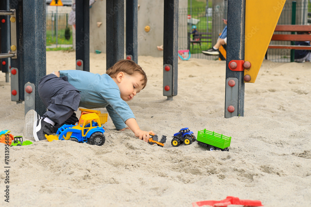 Fototapeta premium child toddler male playing on playground in sand with toys