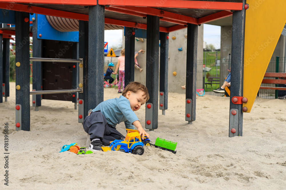 child toddler male playing on playground in sand with toys child toddler male playing on playground in sand with toys
