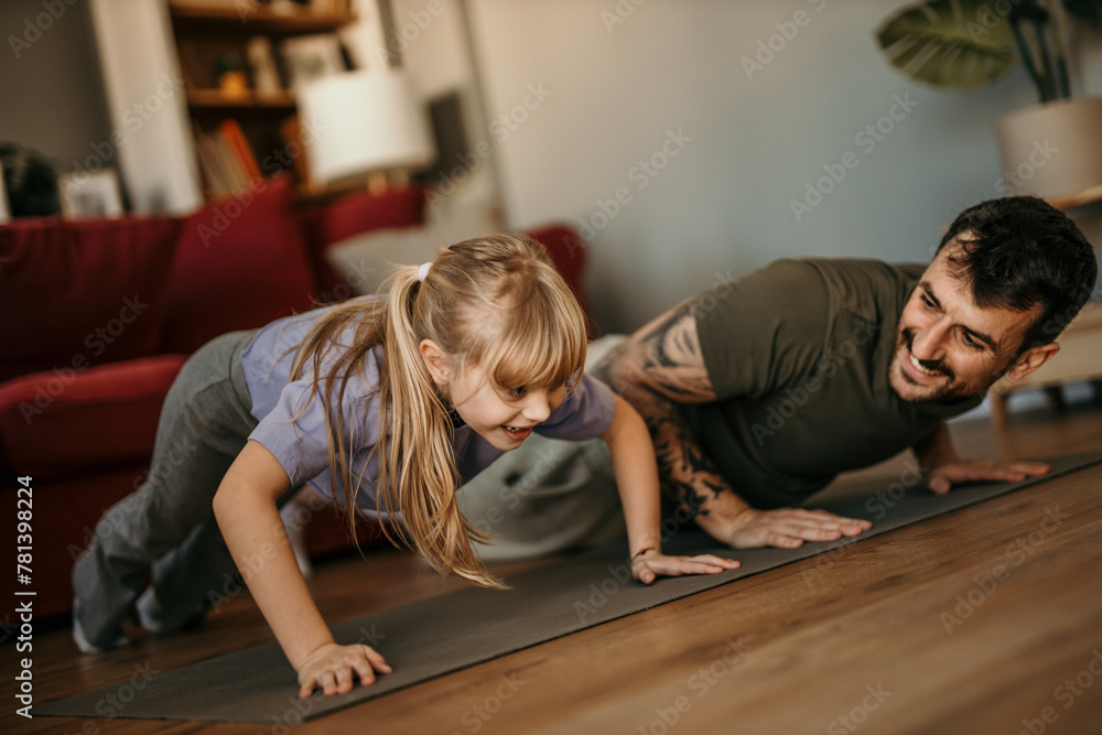 Fototapeta premium Father and daughter doing push ups in the living room