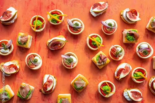 Tartelettes with mozzarella, pea puree, peppers, pesto, red onions and tomatoes photo