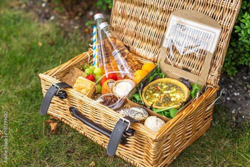 Picnic basket with quiche, salad, rolls and fruit photo