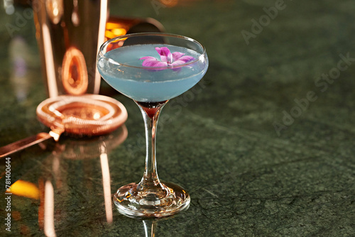 A cocktail with a purple flower garnish