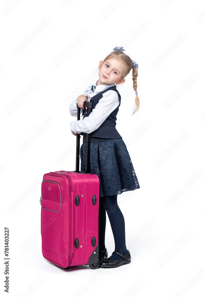 A happy little girl in a school uniform stands with a large pink suitcase, isolated on a white background A happy little girl in a school uniform stands with a large pink suitcase, isolated on a white background