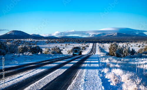 Frozen highway from Grand Canyon National Park to Williams Arizona on a cold sunny winter morning. Snow covered lanes in wide american landscape with oncoming truck. Calm atmosphere with blue sky. photo