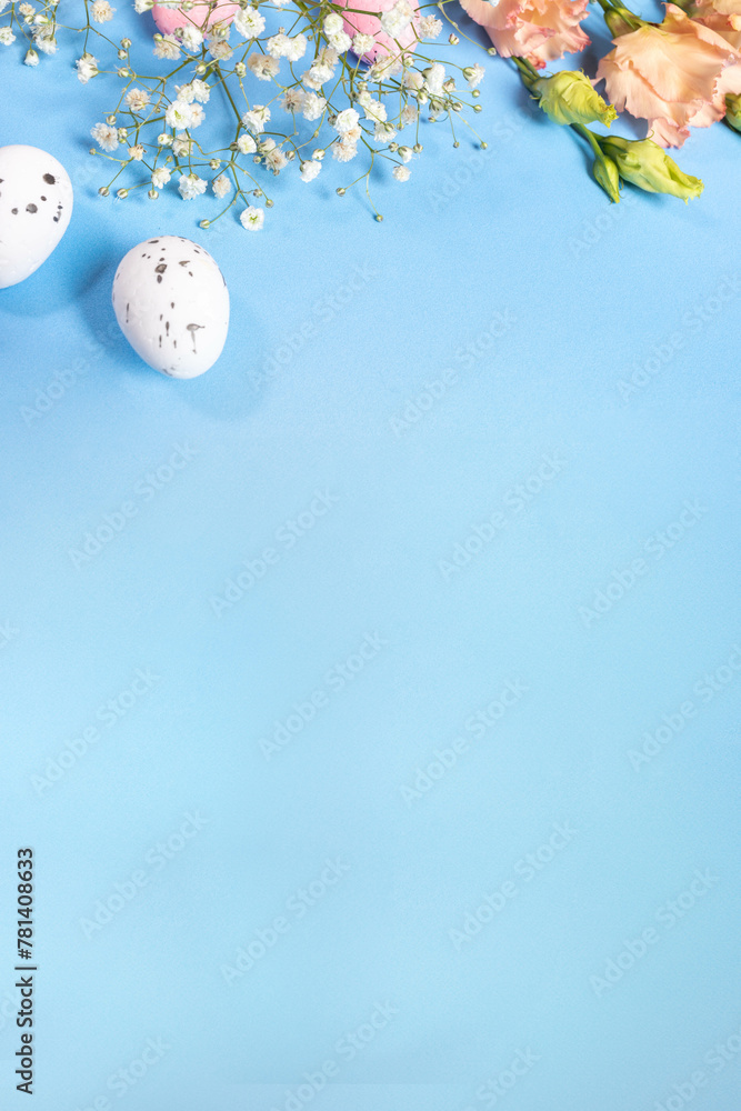 White spotted decorative eggs, gentle flowers on blue. Top view. Vertical Easter card. Copy space.